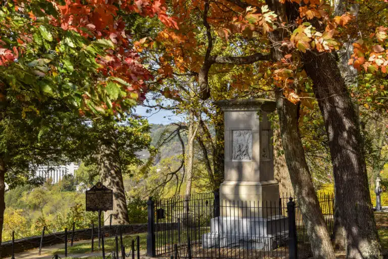 Daniel and Rebecca Boone's stone grave monument in Frankfort Cemetery framed by red and orange autumn trees.