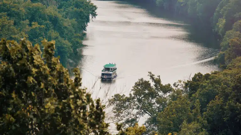 The Bourbon Belle tour boat cruising down the tree-lined Kentucky River in Frankfort, Kentucky.