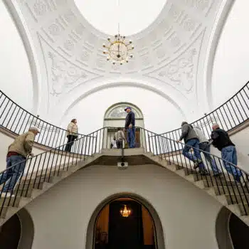 Visitors walk up the double circular stone staircase inside the bright, white rotunda of Frankfort's historic Old State Capitol.