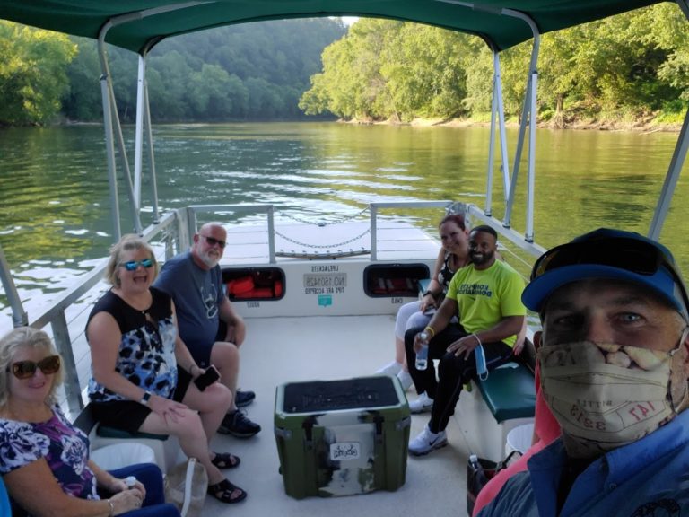 Captain , wearing a mask with a group of happy customers on the boat