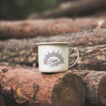 logs for firewood with coffee cup on them that reads Happy Camper
