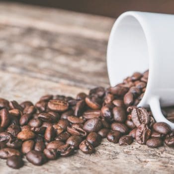 coffee beans on a wood slab, white ceramic mug on side