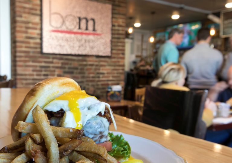 House burger at Bourbon on main- thick beef burger with melted cheese and an egg on top. Bourbon on Main sign and patrons in background