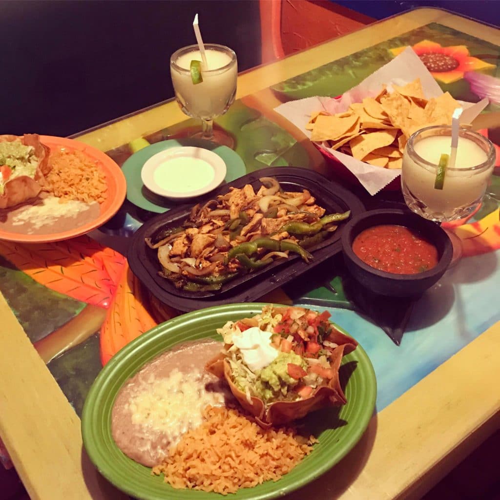 table loaded with Mexican dishes and margaritas