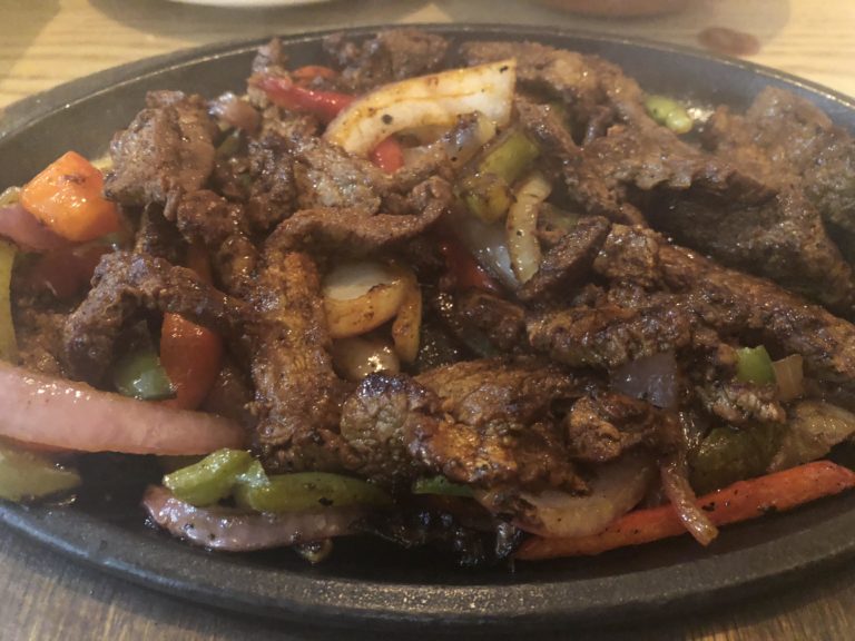 steak fajitas with onions and peppers in a cast iron skillet