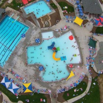 direct overhead shot of aquatic center showing the main poo, splash pad, l lazy river and lap pool