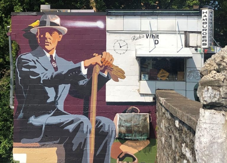 Mural on side of RIck's Diner, featuring a man from what looks to be the 1940's, suit, hat, tie, with a bird on the brim of his hat.