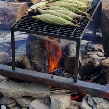 close up shot of a fire with corn cobs roasting on a grill