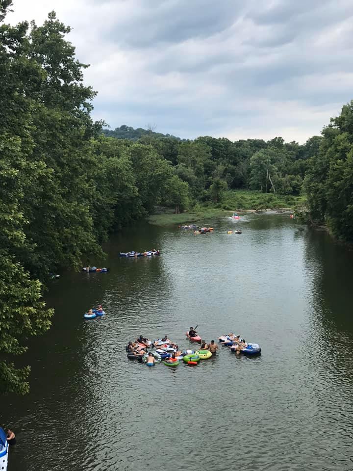 several people floating on different types of rafts in a calm creek