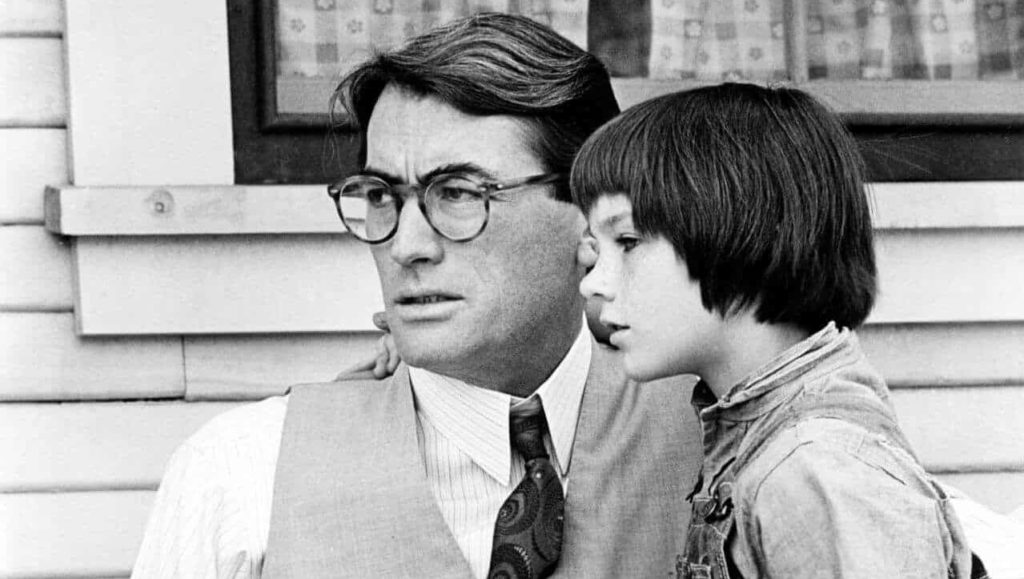 Mary Badham with her arm around Gregory Peck's shoulder in To Kill a Mocking Bird