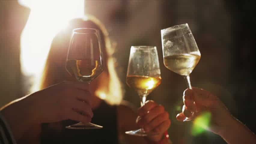 three wine glasses with white wine, toasting