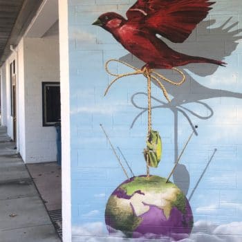Mural featuring a red bird holding the globe by a string