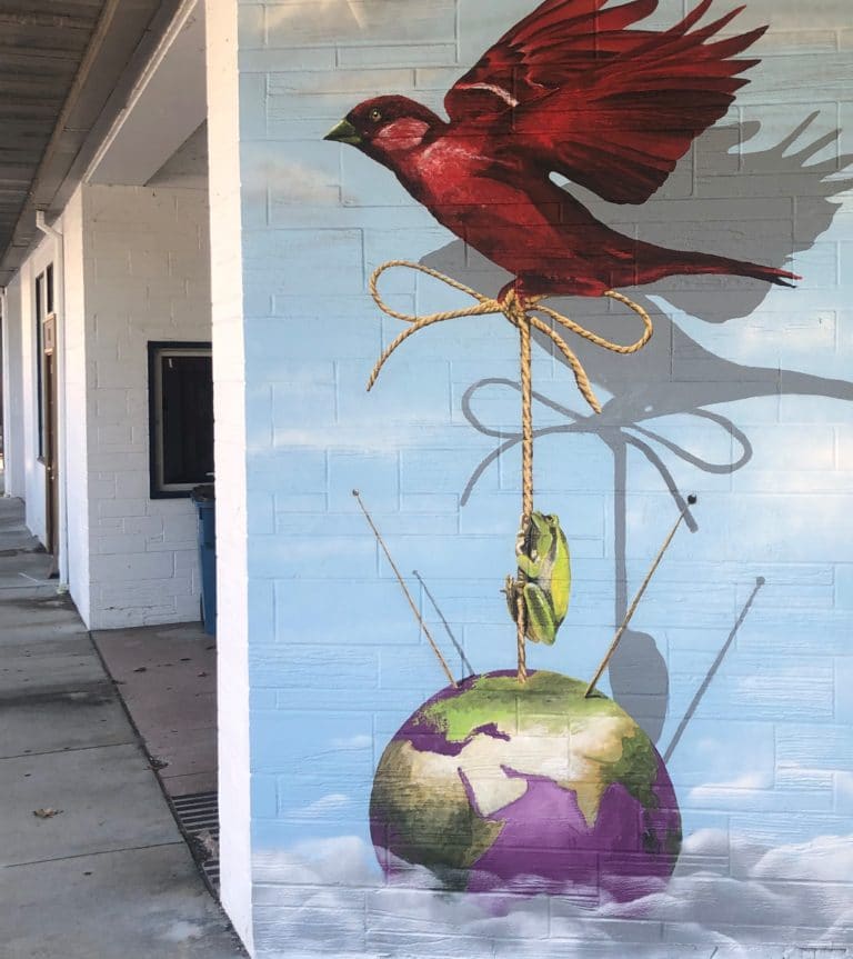 Mural featuring a red bird holding the globe by a string